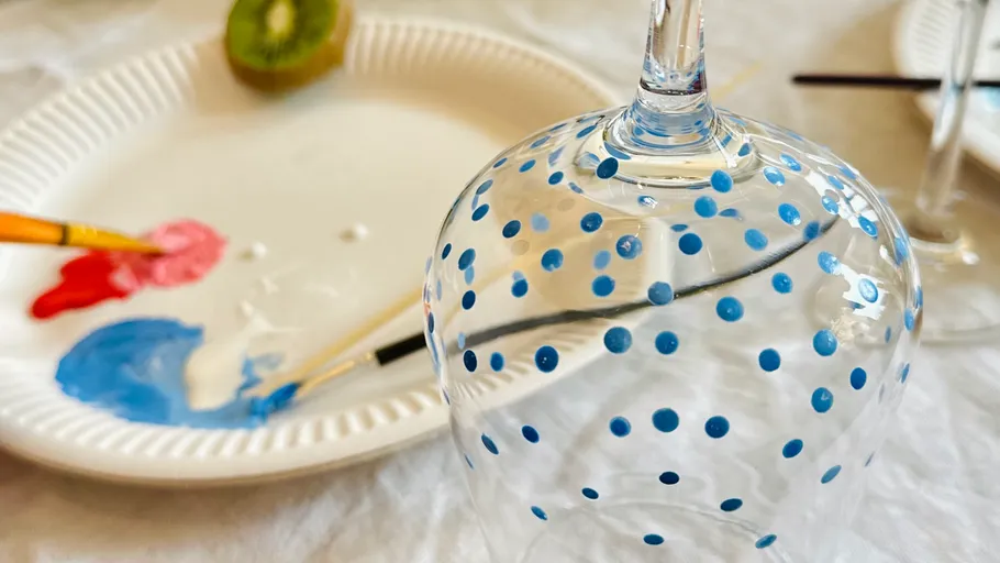 Bemaltes Glas mit blauen Punkten auf Tisch.