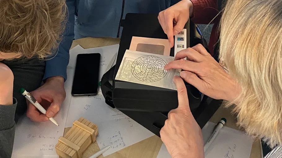 People solving puzzles with papers and a device.
