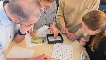 Four people solving puzzle at table.
