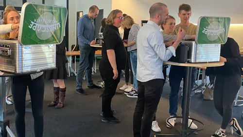 People gathered around tables, interacting with boxes.