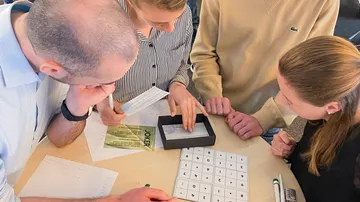 Gruppe löst ein Rätsel, konzentriert auf Papiere.