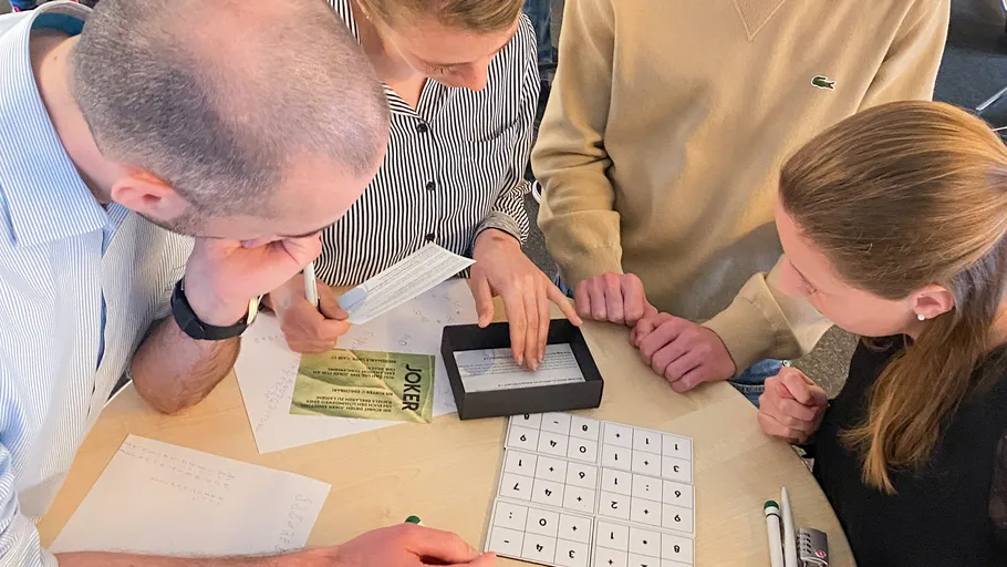 Group solving a puzzle, focused on papers.