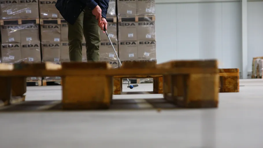 Person playing mini-golf in a warehouse.