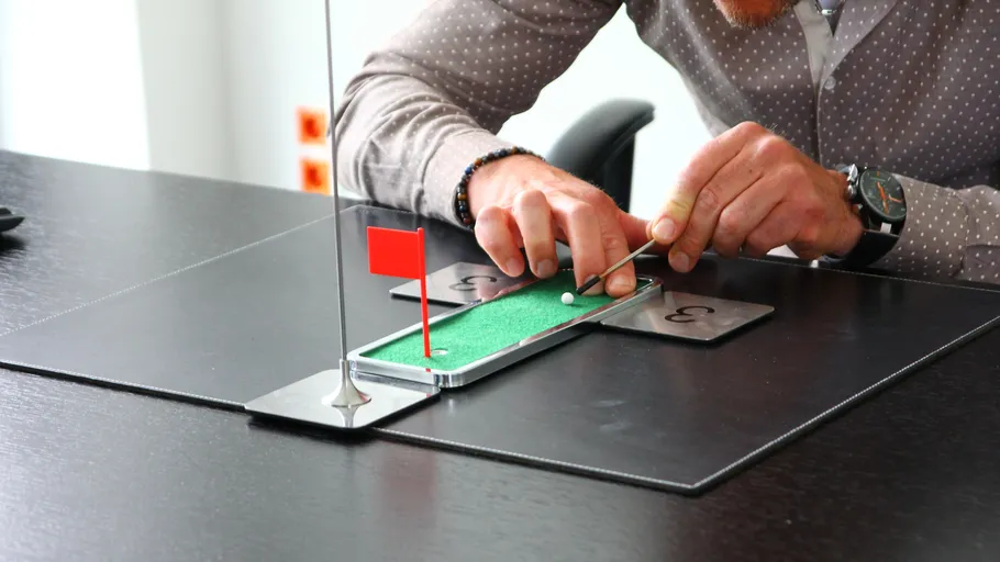 Man playing miniature golf on desk.
