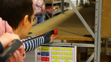Person measures shelf depth in storage room.