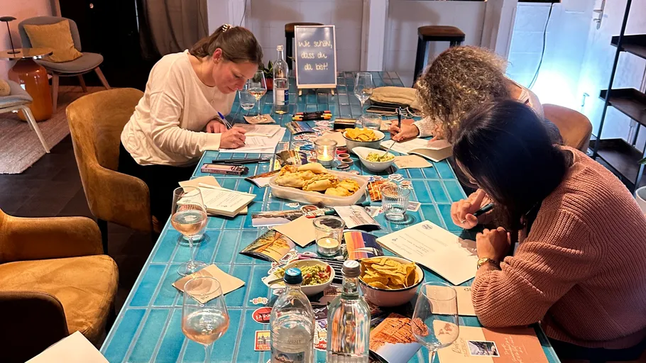Drei Frauen schreiben an einem Tisch mit Snacks.