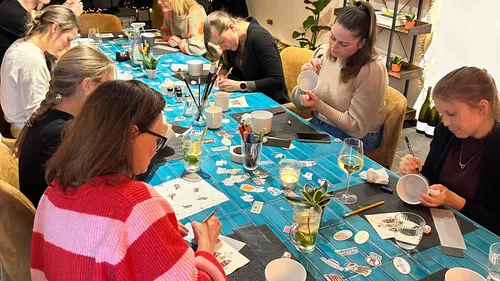 People painting mugs at a table workshop.