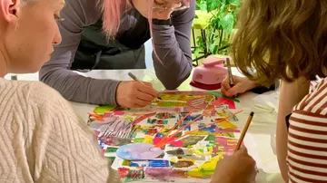 Three people collaboratively create colorful artwork.