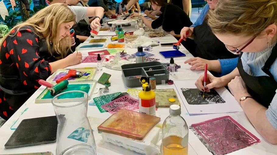 Menschen basteln Kunst an einem langen Tisch.