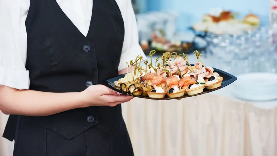 Waiter holding tray of appetizers at event.