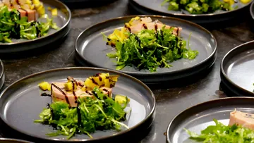 Plates with salad, fish, and mango garnish.