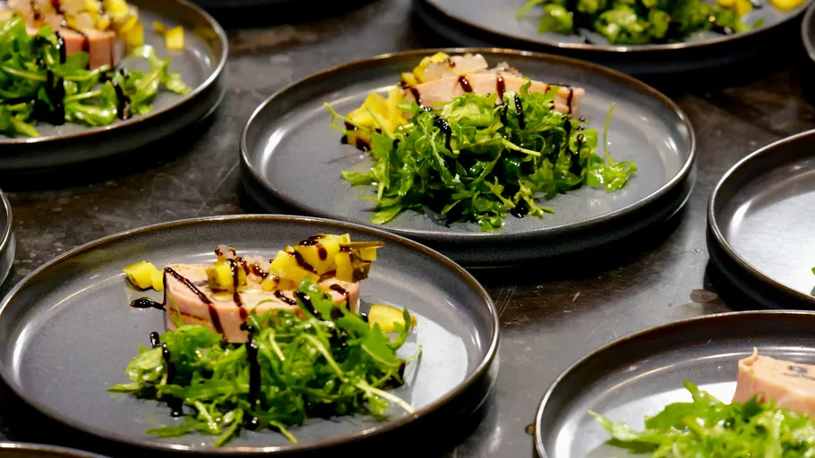 Plates with salad, fish, and mango garnish.