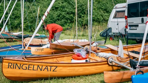 Holzsegelboote auf Gras, Person beim Vorbereiten.