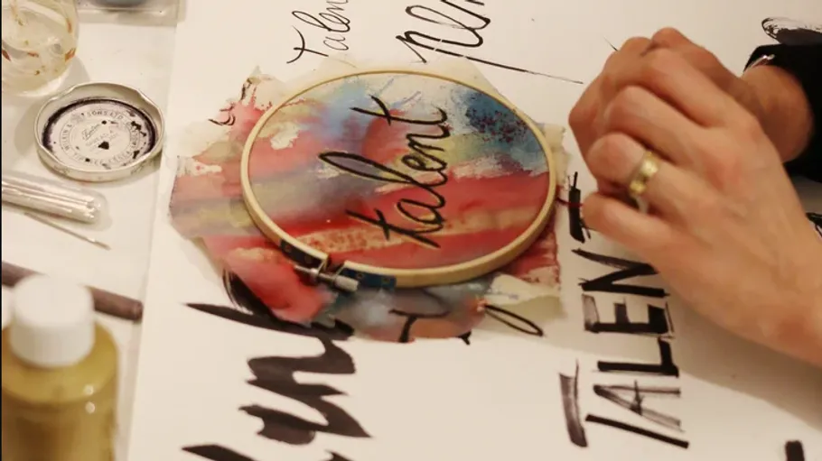 Person verziert Papier mit Text und Stickerei.