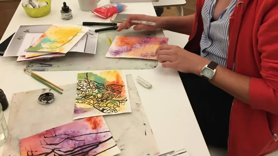 Person creating colorful drawings at table.
