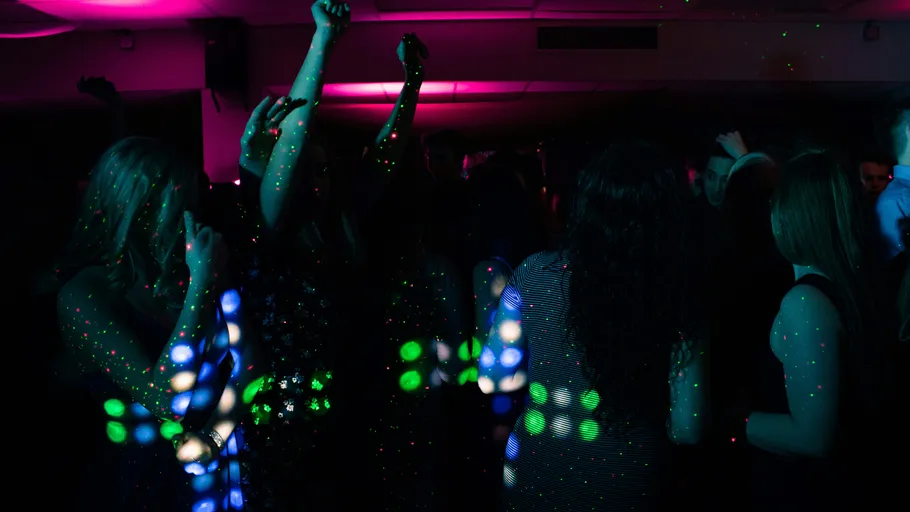 People dancing under colorful lights indoors.