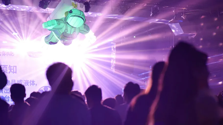 Crowd under inflatable astronaut with purple lights.