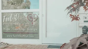Eingang mit Yogainstitut-Schild und Pflanzen.