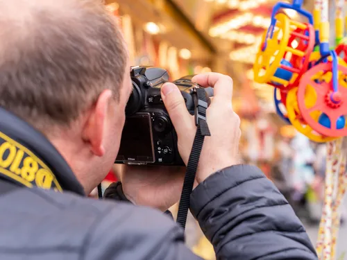 Person fotografiert farbige Objekte auf Jahrmarkt.