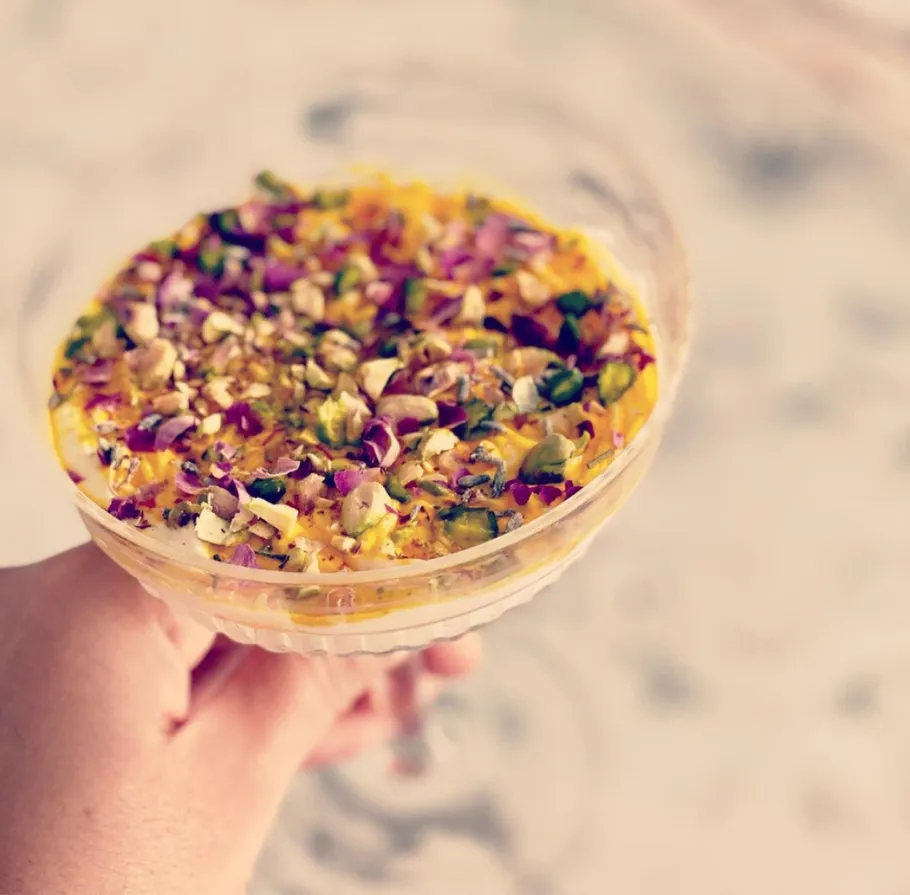 Dessert mit Nüssen und Blüten, in der Hand gehalten.