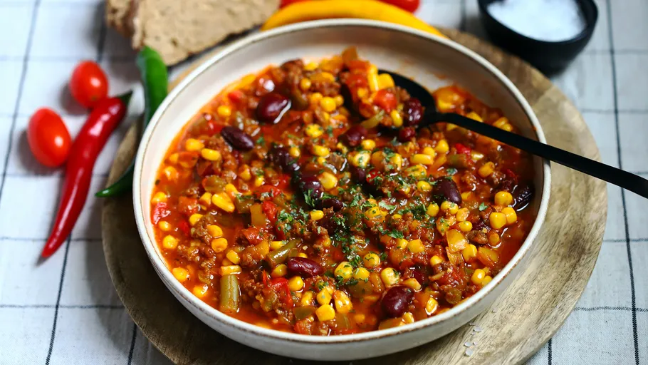 Bowl of chili with beans and corn, table setting.