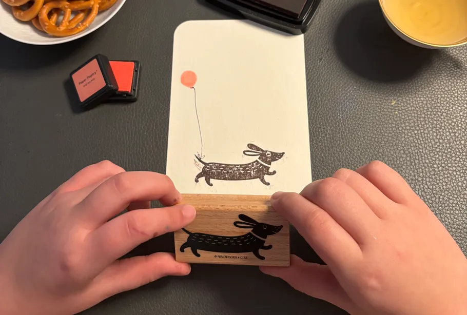 Hands stamping dog image on paper.