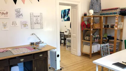 Sewing room with desk, shelves, and decorations.