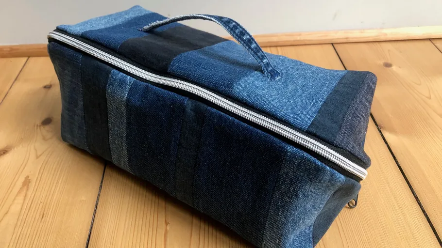 Patchwork denim bag with handle on wooden floor.