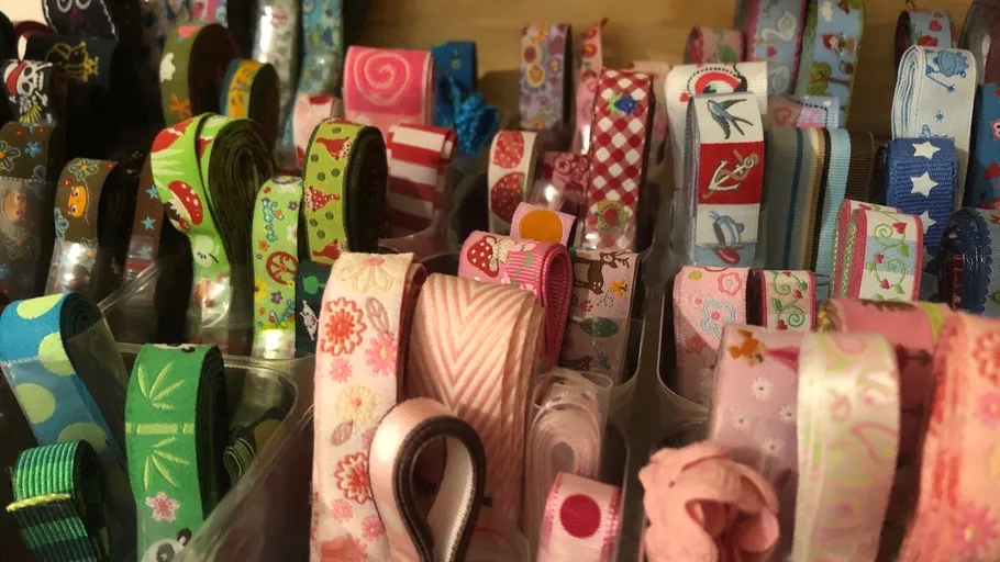 Bunte Bänder in Behältern im Regal gerollt.