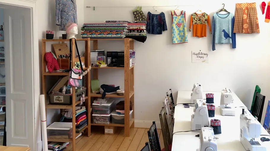 Sewing room with machines and fabric shelves.