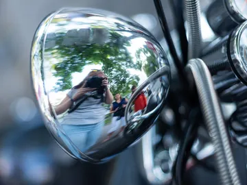 Spiegelbild reflektiert Personen und Bäume in einer Umgebung.