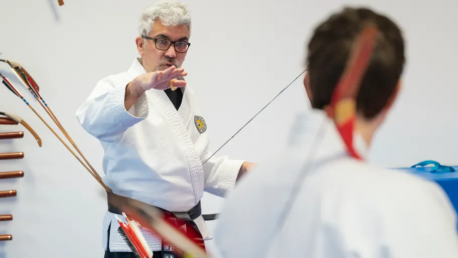 Lehrer unterrichtet Bogenschießen in einem Dojo.