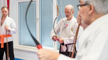 Three men practicing archery indoors.