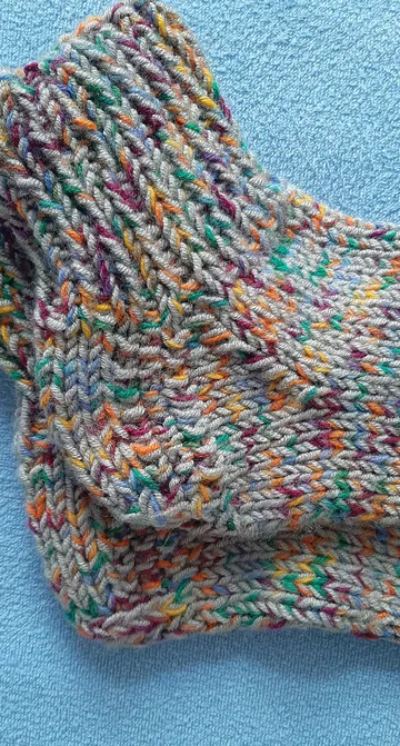 Bunte gestrickte Socken auf blauem Stoff.