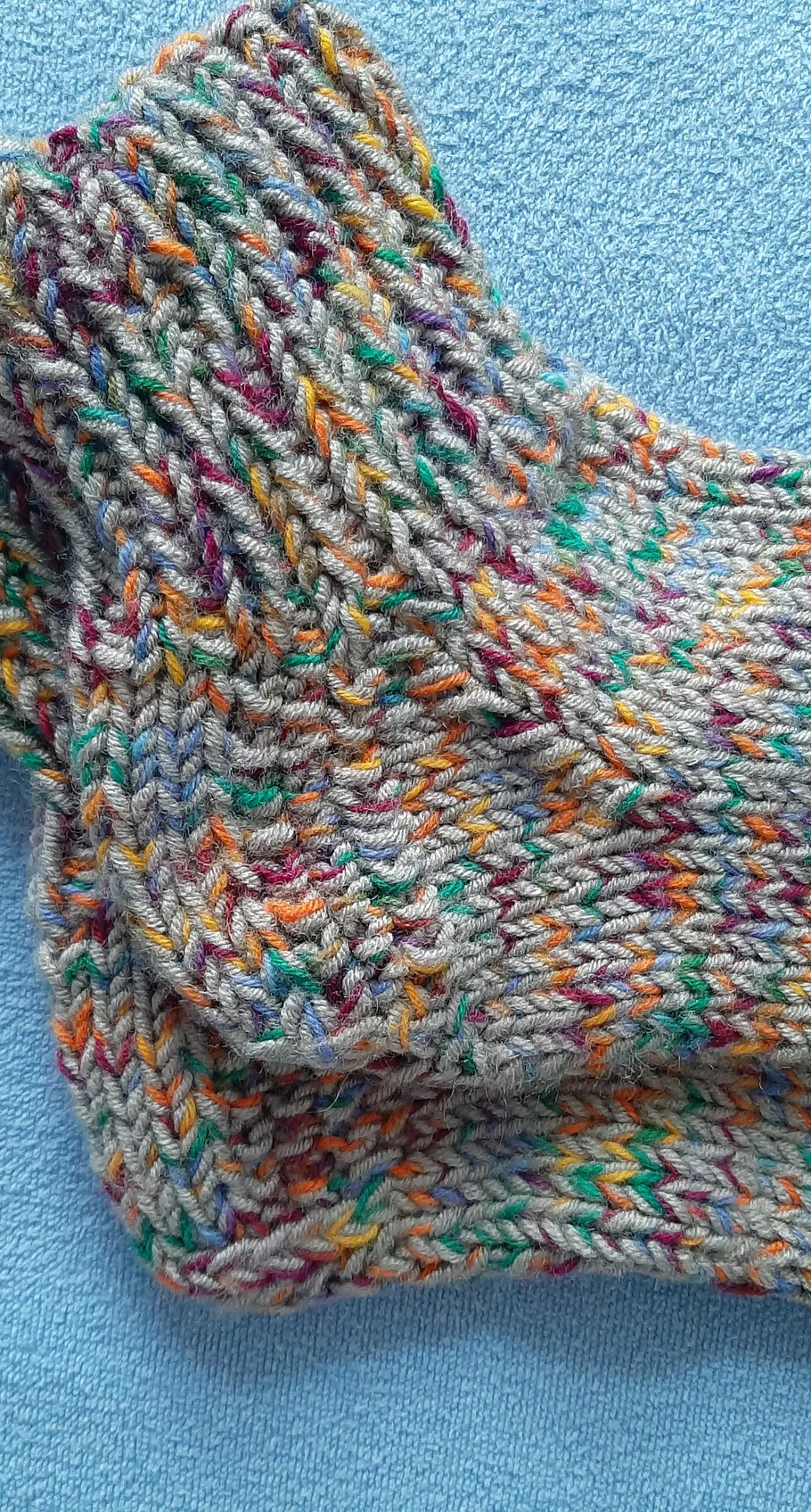 Colorful knitted socks on blue fabric.