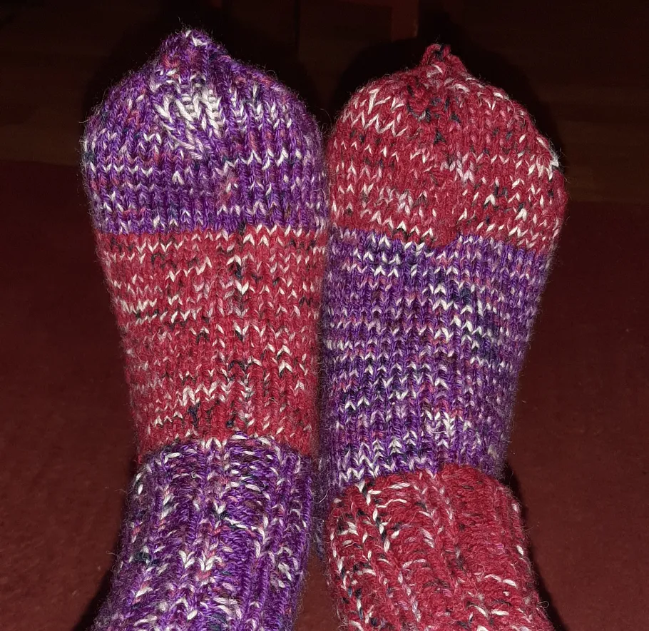 Colorful knitted socks on feet indoors.