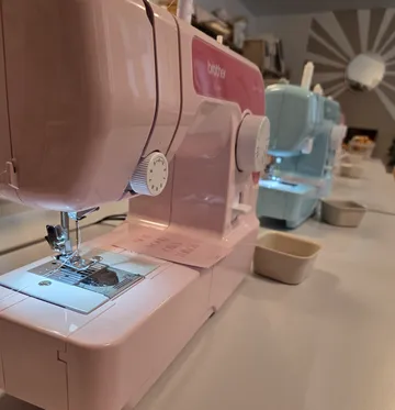Rosa Nähmaschine auf einem Tisch.
