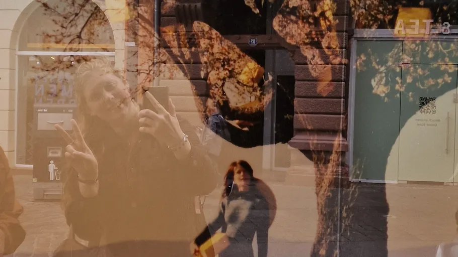 Spiegelung einer Frau beim Selfie, Straße im Hintergrund.