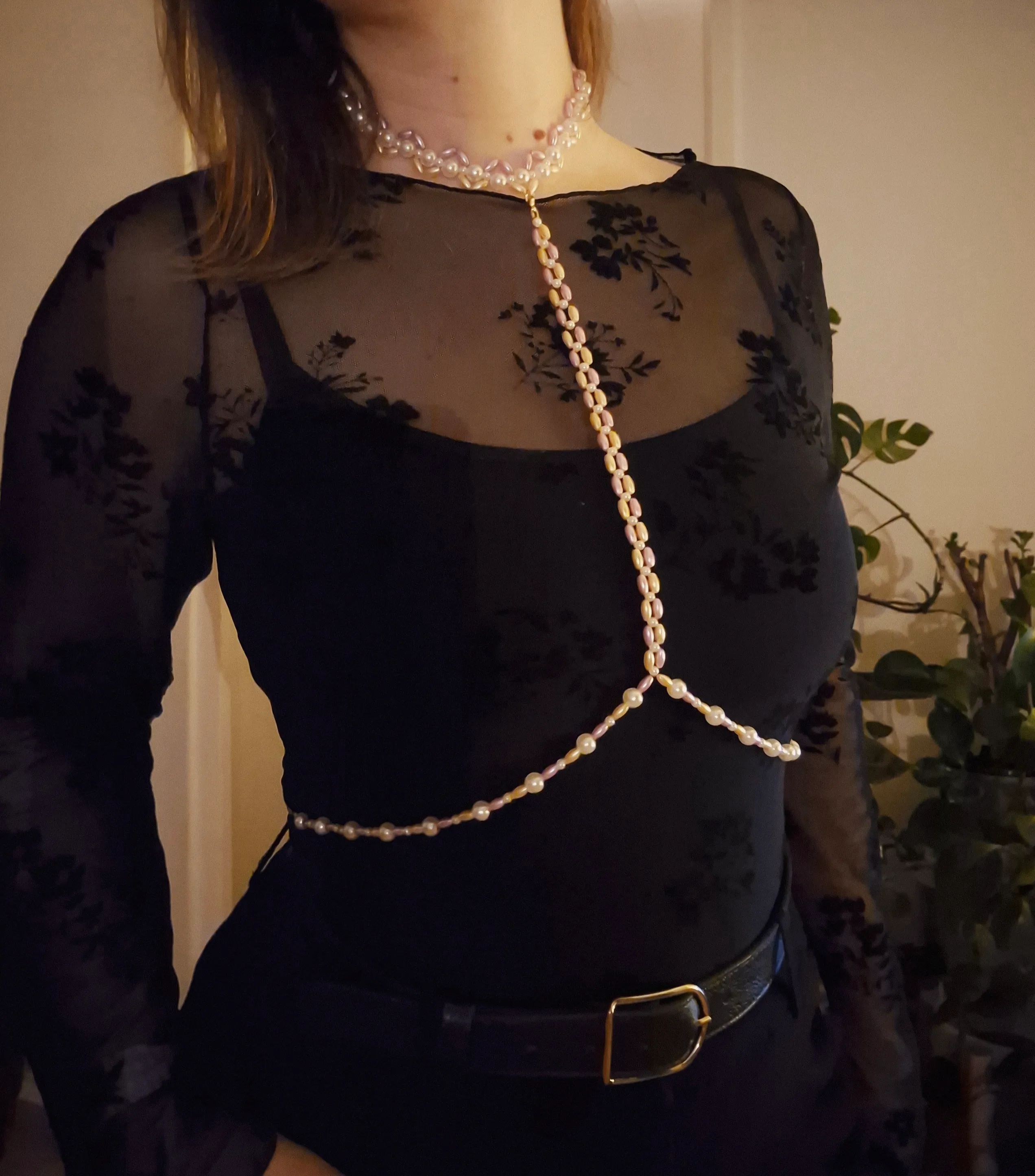 Frau trägt Perlenkette über schwarzem Shirt.