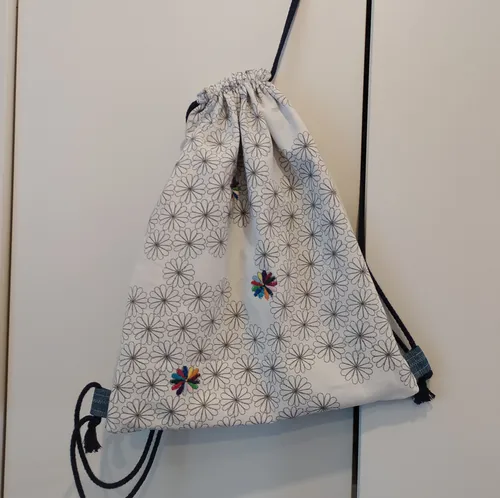Drawstring bag with floral pattern, hanging indoors.