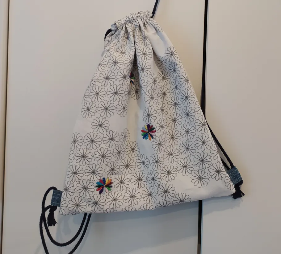 Flower-patterned drawstring bag hanging on door.