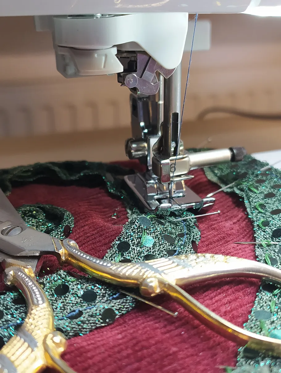 Sewing machine stitching fabric with scissors nearby.