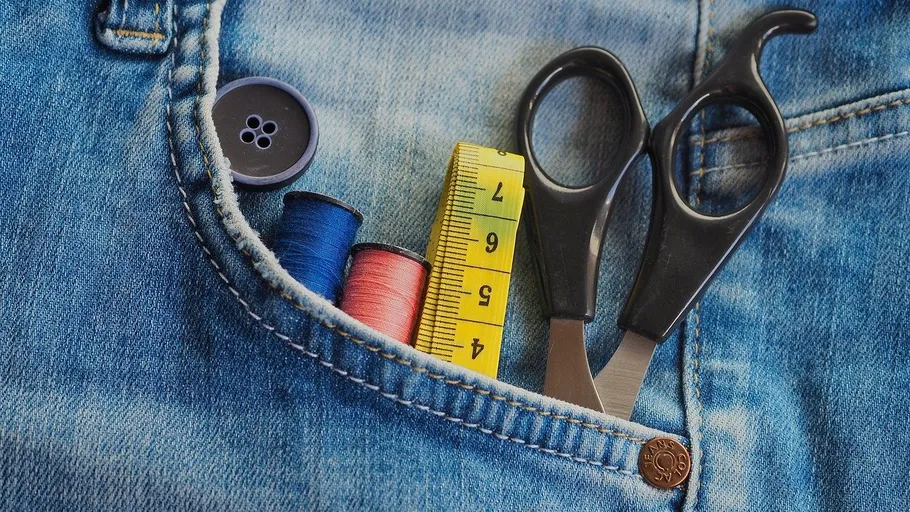 Schere, Fäden und Maßband in Jeans-Tasche.
