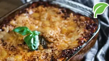 Baked lasagna with basil garnish in a dish.