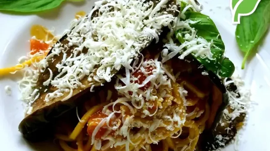 Spaghetti topped with cheese, basil, and eggplant slice.