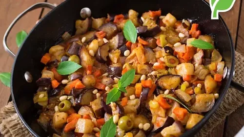 Gemüse-Eintopf in schwarzer Pfanne mit Kräutern.