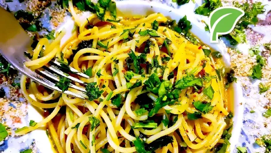 Spaghetti with herbs on a white plate.