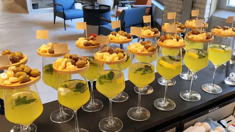 Glasses with yellow drinks topped with cheese and olives.