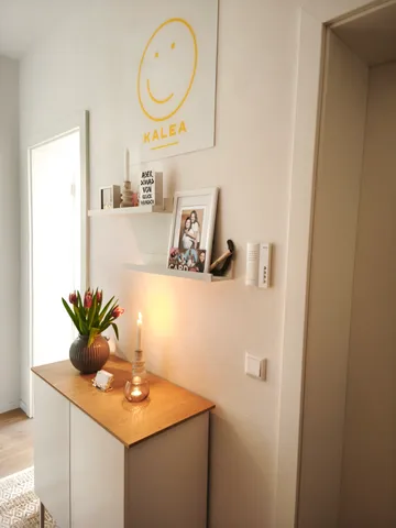 Dekorativer Schrank mit Kerze und Vase.