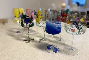 Bunte, handbemalte Weingläser auf Tisch.